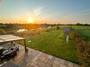 um quintal com uma mesa de piquenique e vista para o pôr-do-sol em Pass the Keys Stunning Cheshire Barn with HotTub em Sandbach