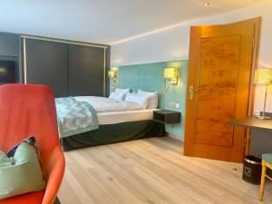 ein Hotelzimmer mit einem Bett und einem Stuhl in der Unterkunft Hotel Reppert in Hinterzarten