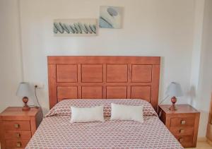 a bedroom with a large bed with two nightstands and two pillows at Apto Julia, 1ª Línea de Playa y Vistas al Mar in Mojácar