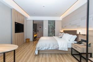 1 dormitorio con cama, mesa y TV en Morning Hotel, Liuyang Country Garden Municipal Government en Liuyang