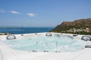 a hot tub with the ocean in the background at Villa Ekphrasis with sea view and jacuzzi in Ravdhoúkha
