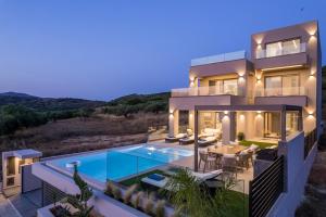 a villa with a swimming pool at night at Villa Ekphrasis with sea view and jacuzzi in Ravdhoúkha