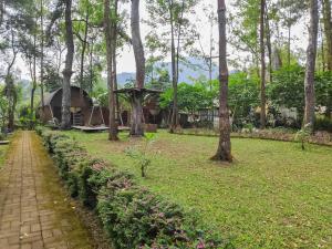 a house in the middle of a park with trees at Chikar Glamping At Wisata Coban Talun Mitra RedDoorz in Junggo