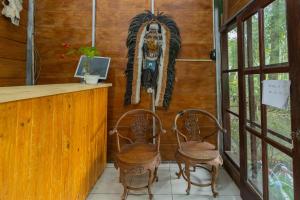 un bar con 2 sillas y una máscara en la pared en Chikar Glamping At Wisata Coban Talun Mitra RedDoorz, en Junggo