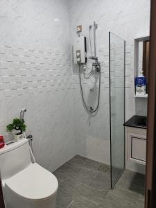 ein weißes Bad mit einer Dusche und einem WC in der Unterkunft Homestay 4BR with Outdoor Pool in Pasir Gudang