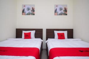2 camas con almohadas rojas en una habitación en RedDoorz near Kawasan Bandara Ahmad Yani Semarang 2 en Kalibanteng-kidul