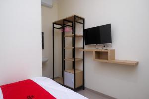 1 dormitorio con TV y estante con TV en RedDoorz near Kawasan Bandara Ahmad Yani Semarang 2 en Kalibanteng-kidul