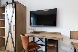 Habitación con escritorio y TV en la pared. en Hotel Baumann en Otterfing