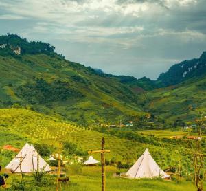a group of tents in a field with mountains at Moon Muong Sang House 