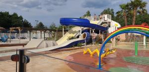 un tobogán de agua en un parque con un arco iris en camping les sables du midi, en Sérignan