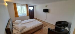 1 dormitorio con 1 cama, 1 silla y TV en Casa Dobric, en Sovata