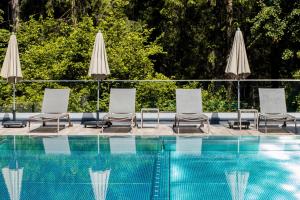 Grupa krzeseł i parasoli obok basenu w obiekcie Aktivhotel Waldhof w mieście Oetz