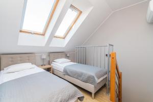 two beds in a attic bedroom with two windows at APARTAMENTY MIERZEJA - STEGNA FOREST, Klimatyzacja, Przyjazne Zwierzętom, Bezpłatny Meleks in Stegna