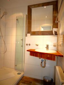 Un baño con lavabo y ducha con espejo. en Vital Lodge Allgäu mit Oberstaufen PLUS, en Oberstaufen