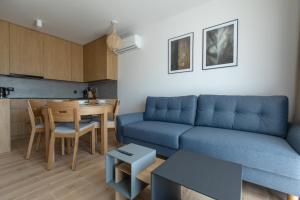 sala de estar con sofá azul y mesa en Apartament Perłowy by Major Domus Club, en Dziwnów