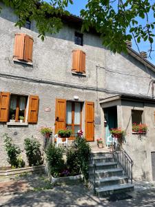 a building with wooden shutters and stairs in front of it at Casa Vacanze Ca' di Lucchini in San Benedetto Val di Sambro