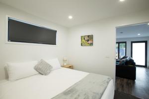 a bedroom with a white bed with a flat screen tv at Mt Field Retreat in National Park