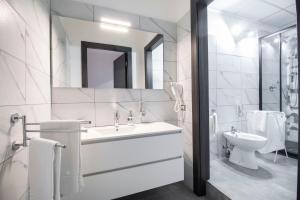 a white bathroom with a sink and a toilet at Royal Playa Suite and Apartament -private parking- self chek out in Catania