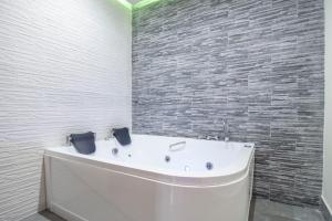 a bath tub in a bathroom with a brick wall at Royal Playa Suite and Apartament -private parking- self chek out in Catania