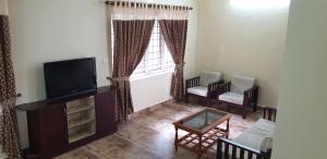a living room with a flat screen tv and chairs at Signature Grande Villa, Kalathipady, Kottayam in Kottayam