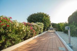 a walkway through a garden with flowers and bushes at Royal Playa Suite and Apartament -private parking- self chek out in Catania