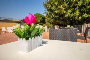 a pink rose in a white vase on a table at Royal Playa Suite and Apartament -private parking- self chek out in Catania