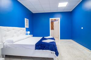 a blue bedroom with a white bed and a blue wall at Royal Playa Suite and Apartament -private parking- self chek out in Catania