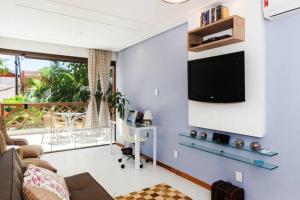 uma sala de estar com uma secretária e uma televisão na parede em Cond Enseada - Belissímo Vista Mar na Praia do Forte em Praia do Forte