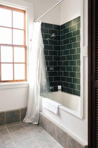 bagno con vasca e parete piastrellata verde di The Townhouse - Historic in the heart of L'ton a Launceston