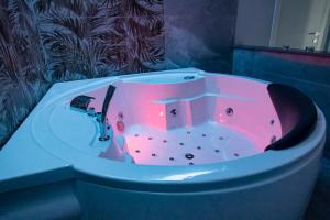 a bath tub with a pink lighting in a bathroom at Royal Playa Suite and Apartament -private parking- self chek out in Catania