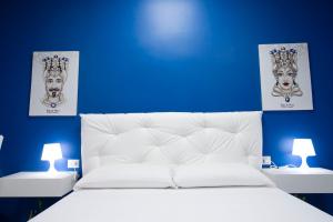 a blue bedroom with a white bed with two pictures on the wall at Royal Playa Suite and Apartament -private parking- self chek out in Catania