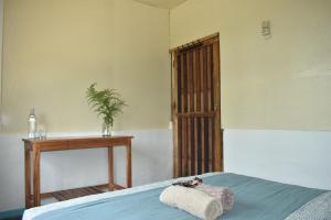 Un dormitorio con una cama y una mesa con una planta en Mama's Homestay Ruteng, en Ruteng