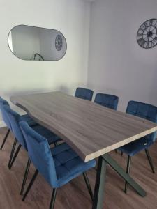 a wooden table with blue chairs in a room at Bagworth House - Spacious 4BR Bungalow in Leicestershire 