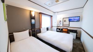 a hotel room with two beds and a desk at Toyoko Inn Chubu International Airport No 2 in Tokoname