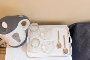 a tray with utensils and a tea set on a table at PURE URBAN BEDBOXES ACROPOLIS METRO PETRALONA in Athens