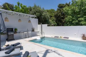 a swimming pool in a backyard with a white fence at Villa Venetia with Jacuzzi in Lambiní