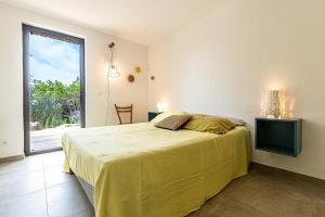 una camera da letto con un letto e una porta scorrevole in vetro di Villa Valle di Corte - Avec piscine et vue mer a Pianottoli-Caldarello