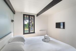 a white bedroom with a large white bed with a window at La Fleur du Moulin - Charmante maison avec jardin proche plage in Saint-Briac-sur-Mer
