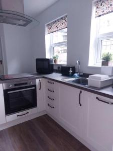 a kitchen with white cabinets and a sink at LetAway - Yonge's Place Saltburn in Saltburn-by-the-Sea