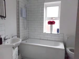 ein weißes Bad mit einer Badewanne, einem Waschbecken und einem Fenster in der Unterkunft LetAway - Yonge's Place Saltburn in Saltburn-by-the-Sea