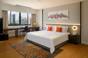 a bedroom with a bed and a desk with a computer at PARKROYAL Suites Bangkok - SHA Plus Certified in Bangkok