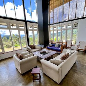 una gran sala de estar con sofás y ventanas. en The Farmhouse Mahaulpatha en Bandarawela