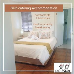 a bedroom with a bed with white sheets and pillows at Paddabult Self Catering Cottages in Paarl