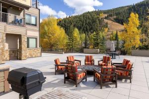 eine Terrasse mit Grill, Stühlen und Tisch in der Unterkunft 2800 Slopeside condo in Keystone