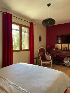 - une chambre avec des rideaux rouges, un lit et un bureau dans l'établissement Les Jardins d'Holi appartement proche Uzès, à Garrigues-et-Sainte-Eulalie