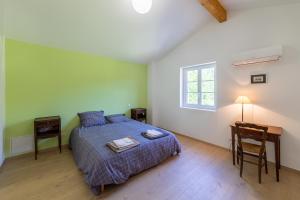 a bedroom with a bed and a desk and a window at La maison dans la nature - Cadre exceptionnel au bord de cours deau in Sainte-Livrade-sur-Lot