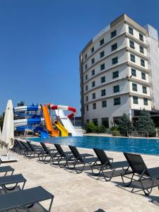 a pool with a slide and chairs and a water slide at The Sign Kocaeli Thermal Spa Hotel &Convention Center in Yeniköy