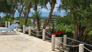 a fence with a bench and flowers and the ocean at Banana Sunset Villas in Paphos