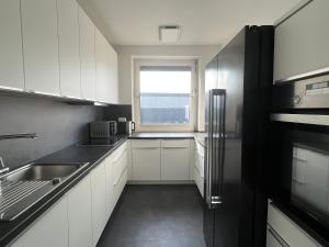 a kitchen with white cabinets and a sink and a window at "Live Good, Work Good" - Stadion Apartment by GG Rental Hamburg in Hamburg