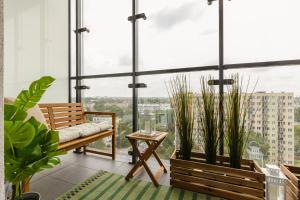 a balcony with a bench and plants and a large window at Wola Business Studios Kasprzaka by Renters in Warsaw